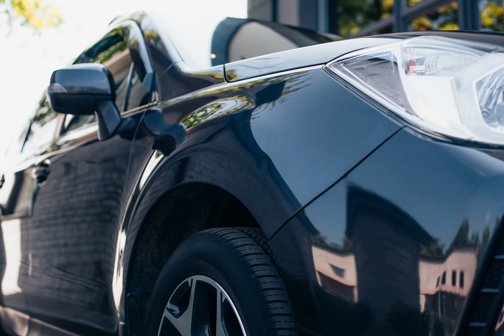 Close-up view of a black car’s front side, featuring the wheel, headlight, and glossy reflections—showcasing the shine achieved by professional Car Detailing Services in Kenner.