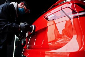A person uses a brush to clean the interior center console of a car, focusing on the area near the gear shifter and control buttons—showcasing the thoroughness of Car Detailing Services in Madisonville.