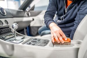A person wearing gloves and a face mask uses a polishing machine on the rear of a shiny red car, showcasing the precision of Car Detailing Services in Madisonville.