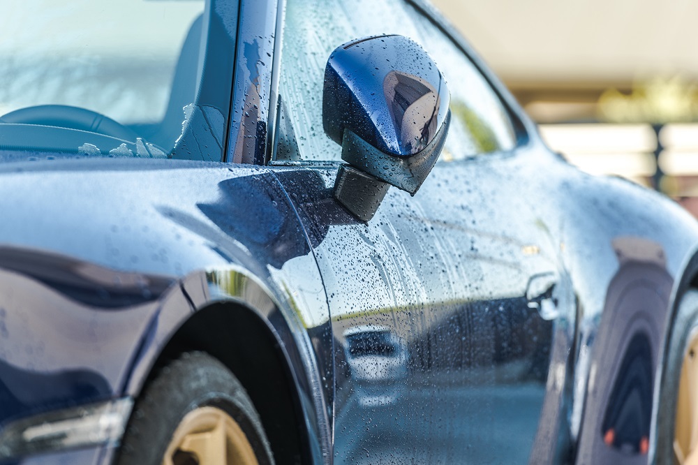 A side view mirror of a car, freshly cleaned and gleaming after a Mobile Exterior Detailing New Orleans service.