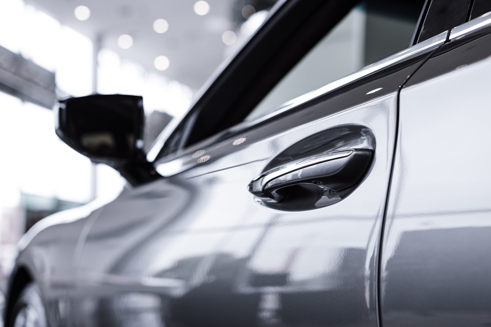 Close-up of a silver car’s driver-side door and handle, with the side mirror visible, taken indoors with soft lighting and blurred background—showcasing the flawless finish achieved by Ceramic Coating New Orleans.